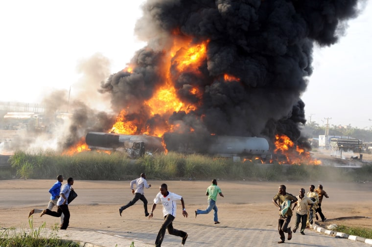Image: Pedestrians run from the scene of a fire ravaging four fuel tankers on Lagos' Ibadan highway on May 11.